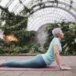 o Renascimento da alma plenitude na terceira idade. Mulher idosa deitada, mãos no solo,e corpo levantado fonte agua atrás